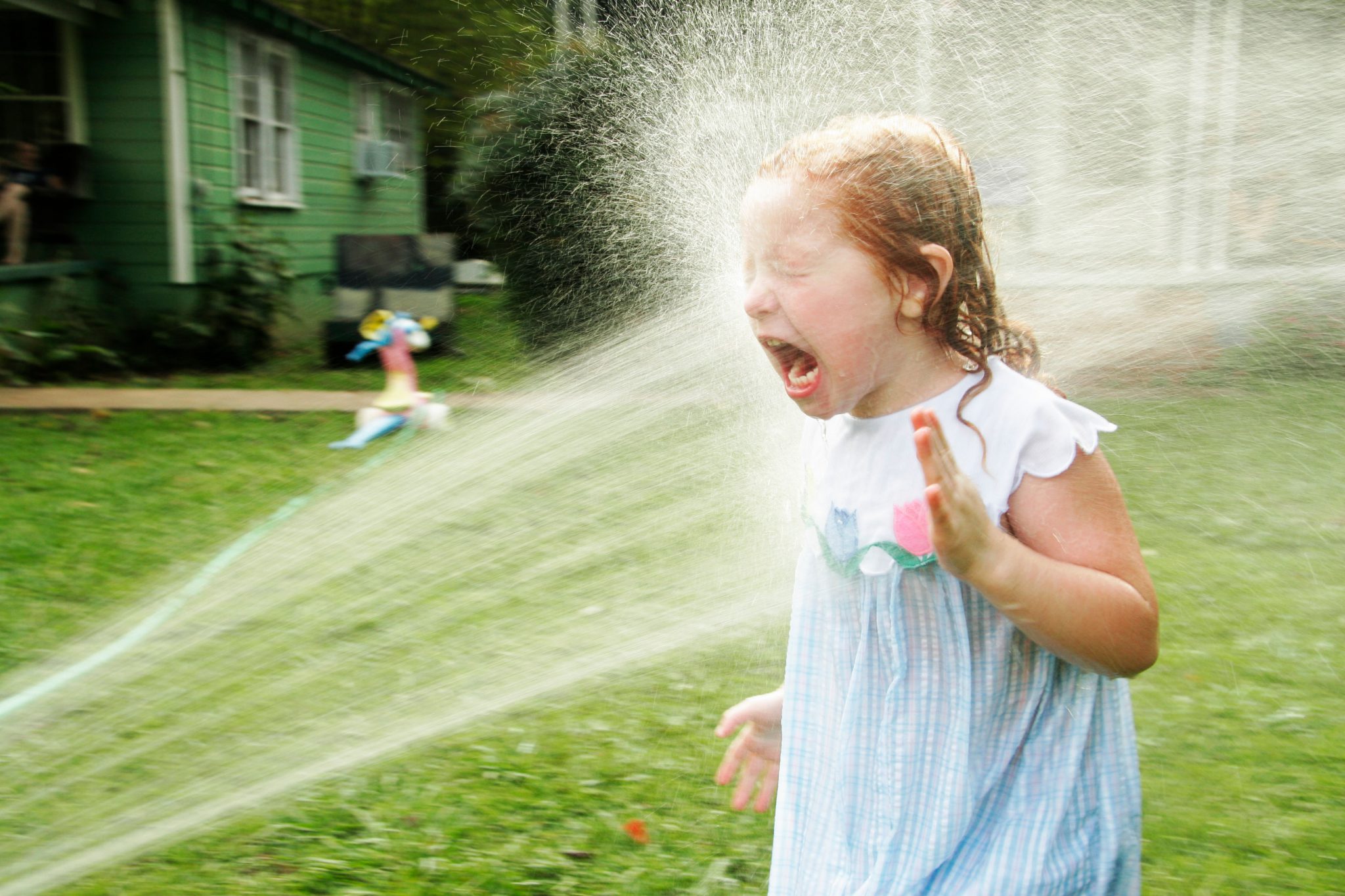 A little girl getting sprayed by a stream of water.
